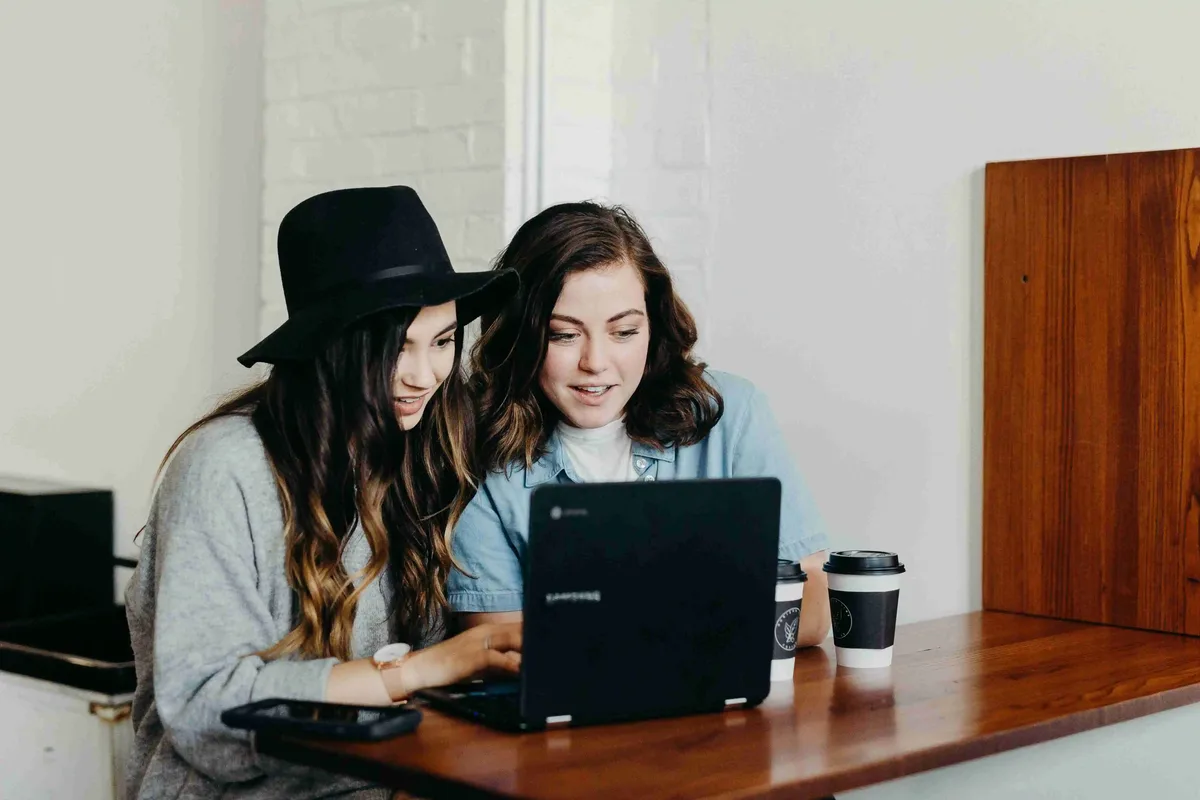 Two people sitting together at a table, looking at a laptop during a one-to-one support session