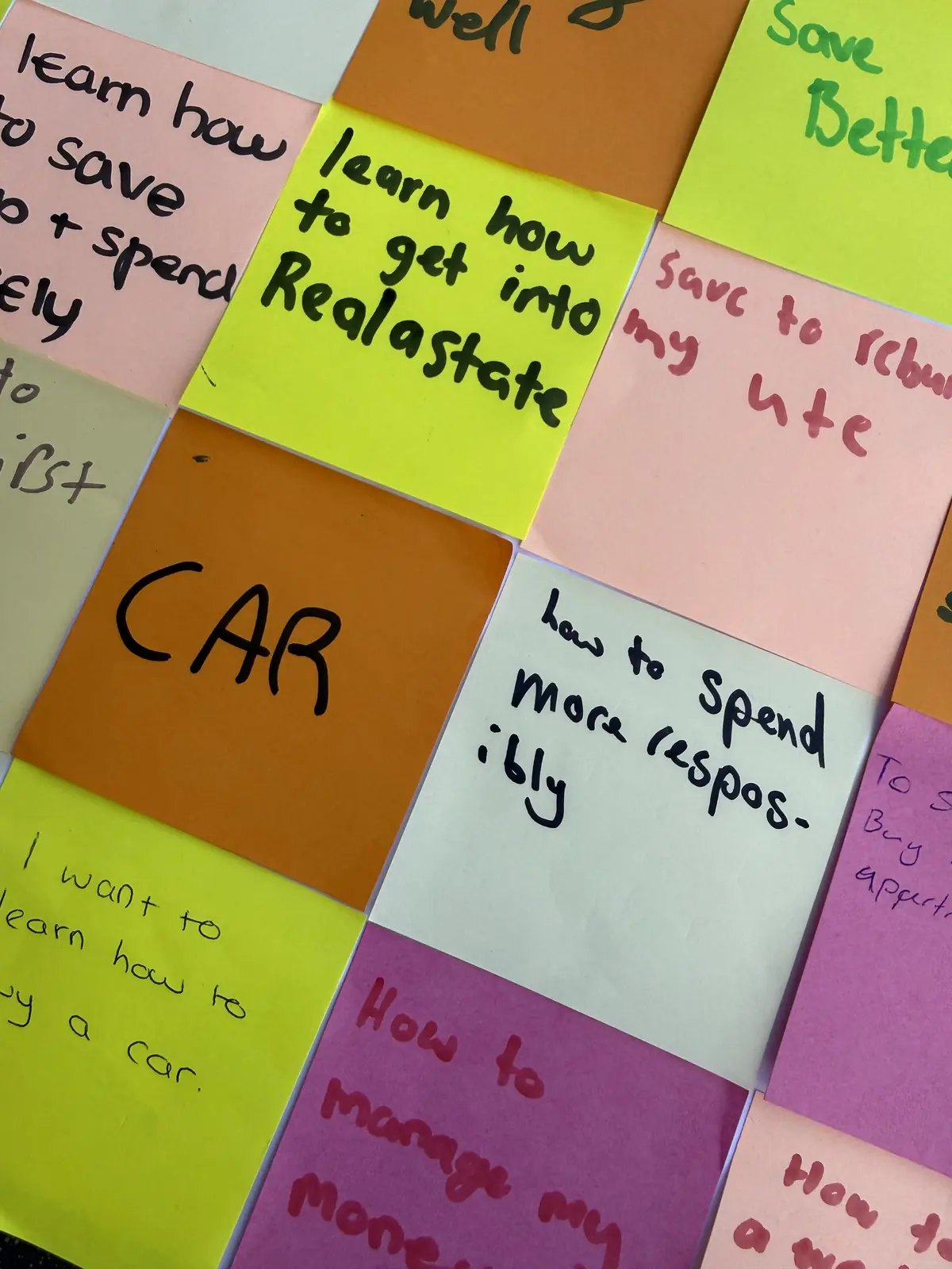 Students setting money goals on sticky notes during a school workshop