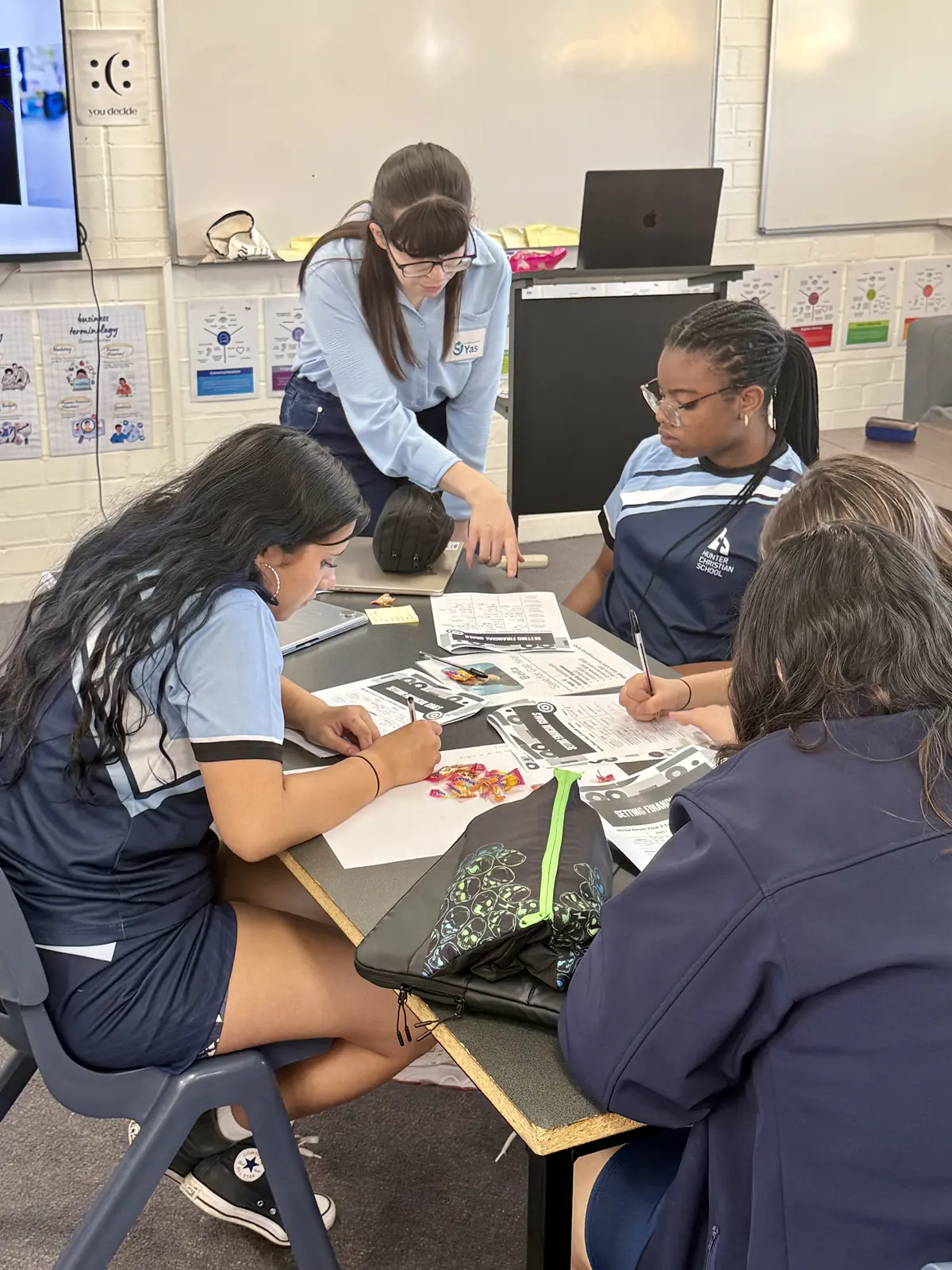 A facilitator helping students through a worksheet activity in a school workshop